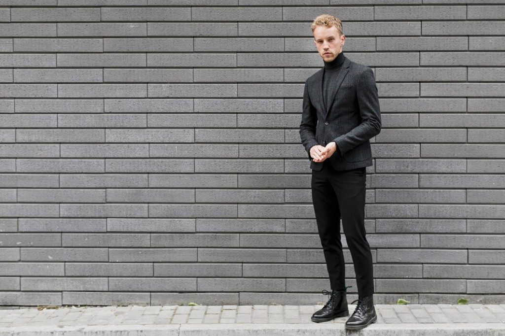 man standing near wall wearing black pant