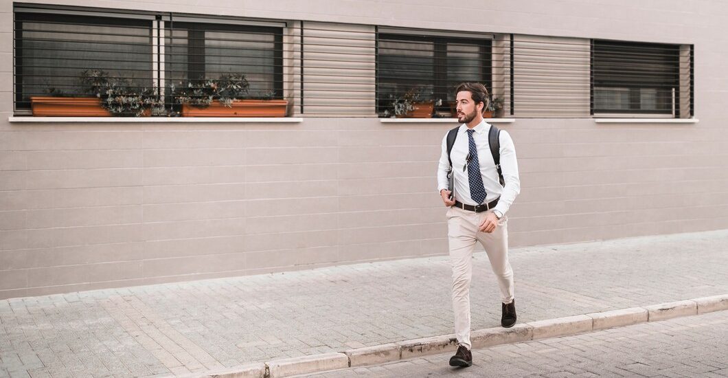 man crossing street wearing cream pant with bag