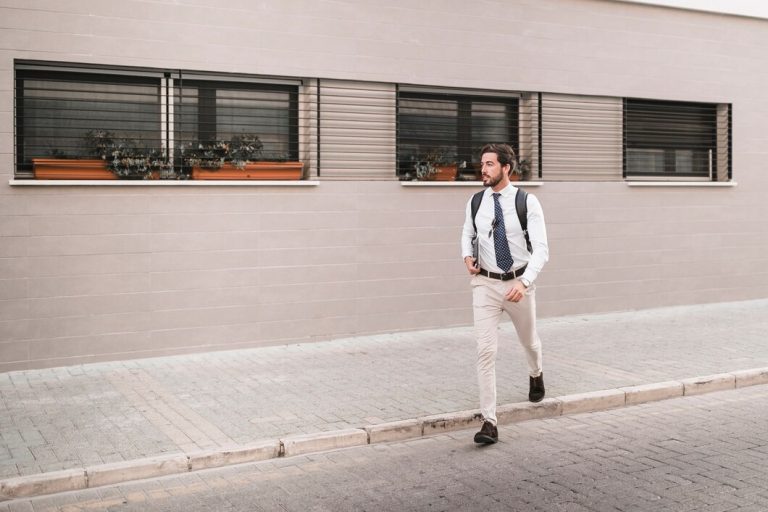 man crossing street wearing cream pant with bag