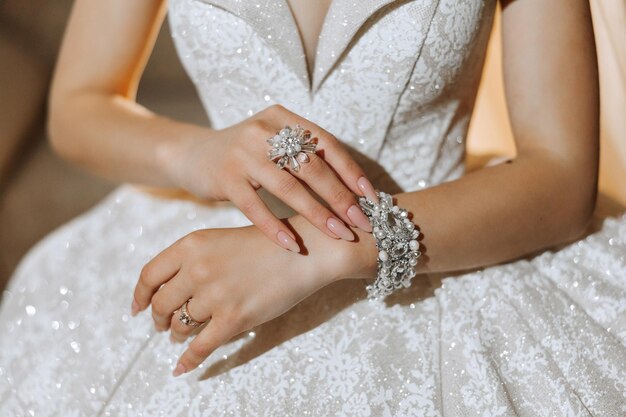 Bride in a white gown wearing a sparkling bracelet and floral statement ring.